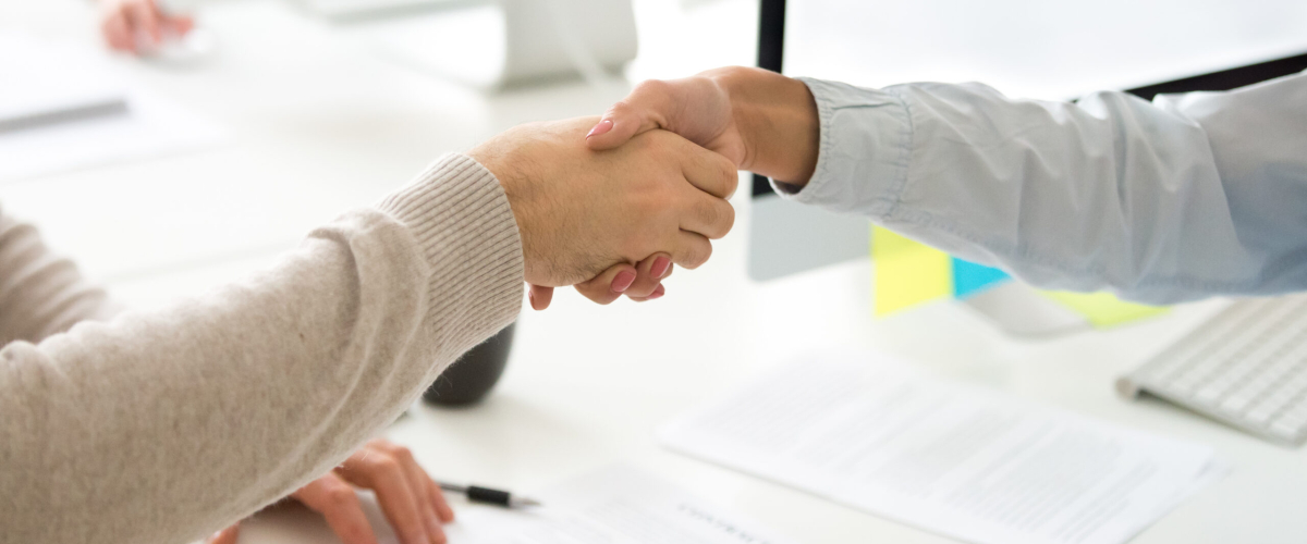 Handshake of man and woman after signing business contract, businessman and businesswoman shaking hands making employment agreement or hiring, buying insurance or becoming partners, close up view